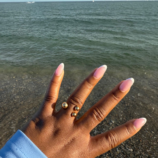 Hand wearing waterproof gold rings  by Herae on a beach