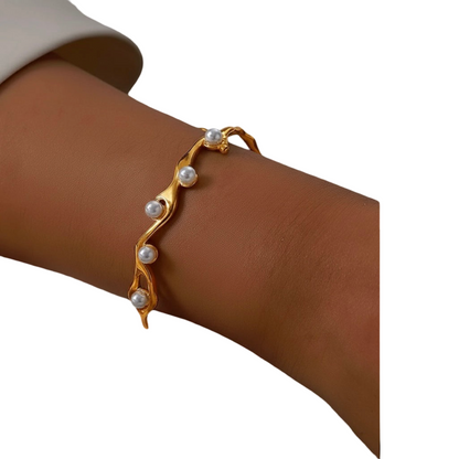 Gold bracelet with pearls on a wrist against a white background