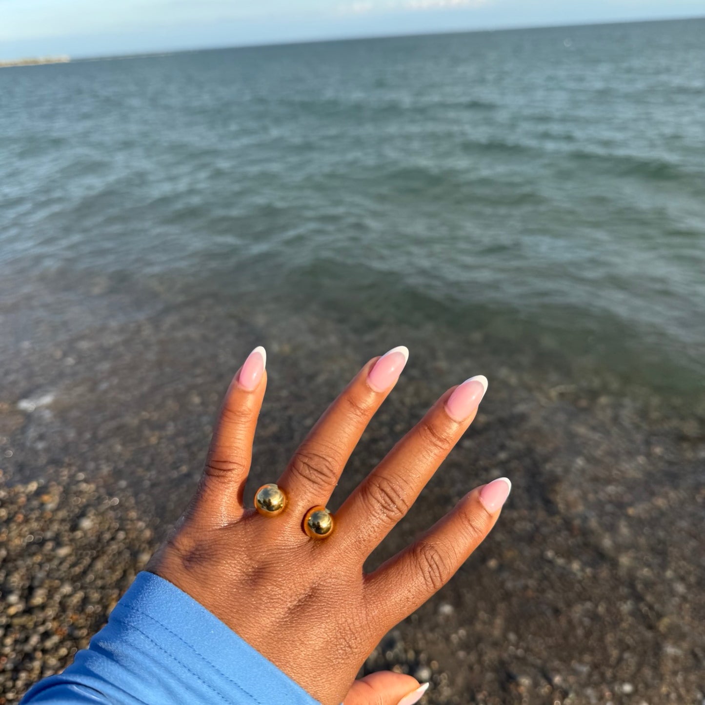 Hand with gold rings on a beach