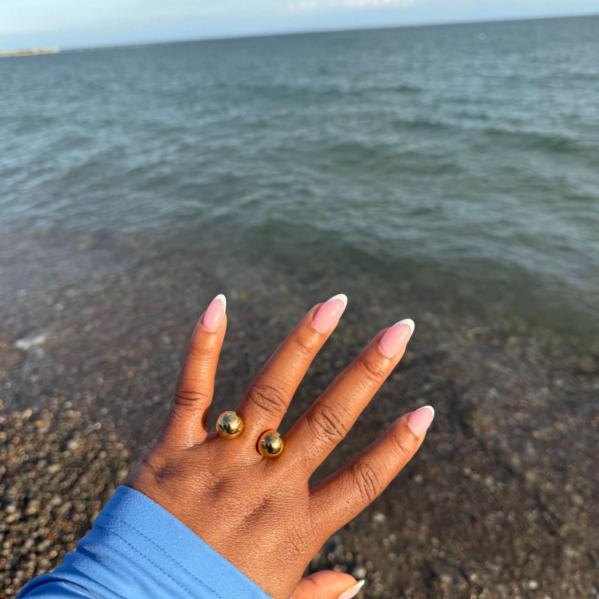 Hand with gold rings on a beach