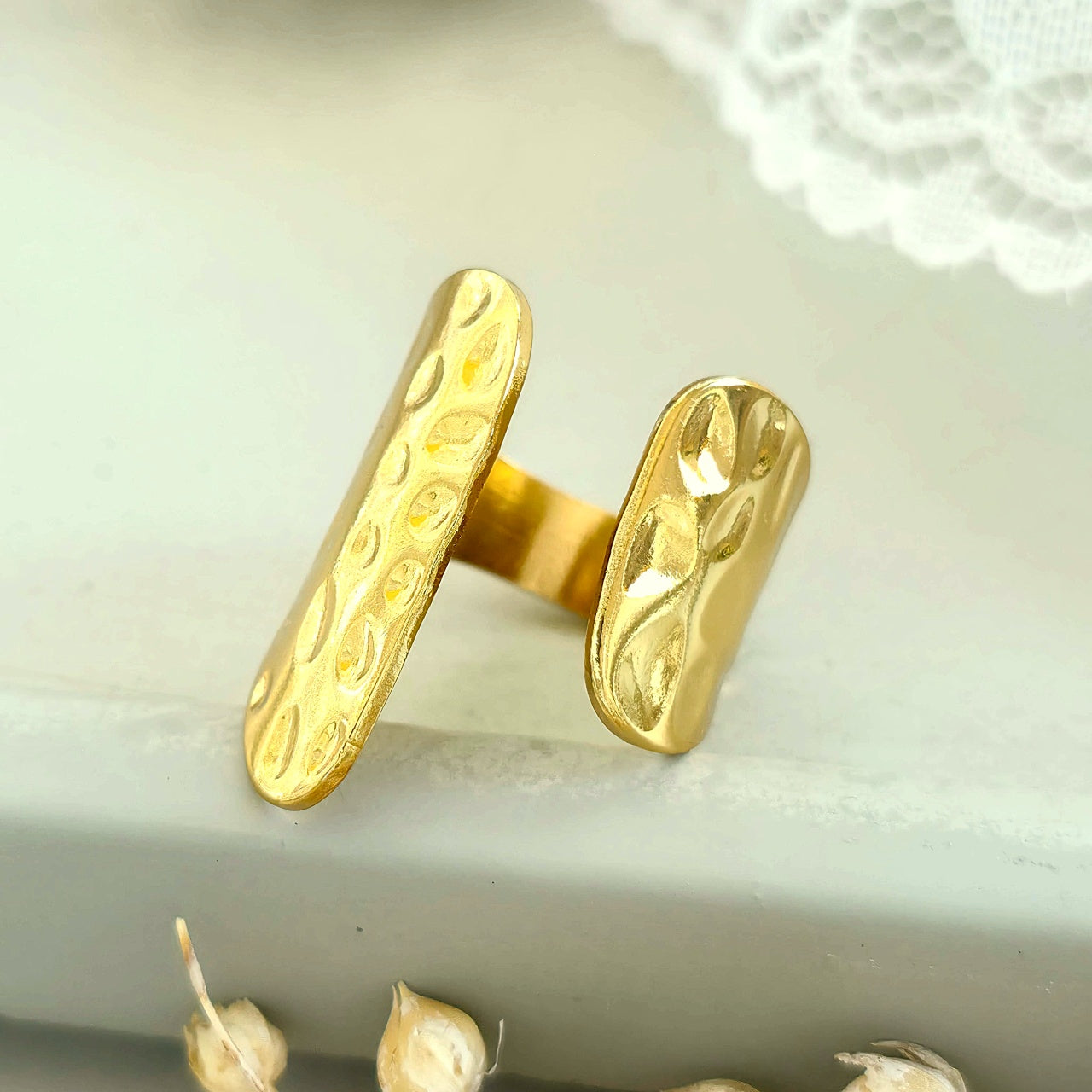 Gold ring with intricate design on a white surface