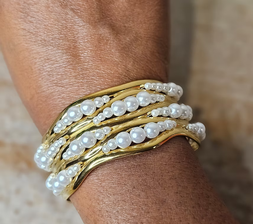 18k Gold and pearl bracelet on a wrist with a neutral background