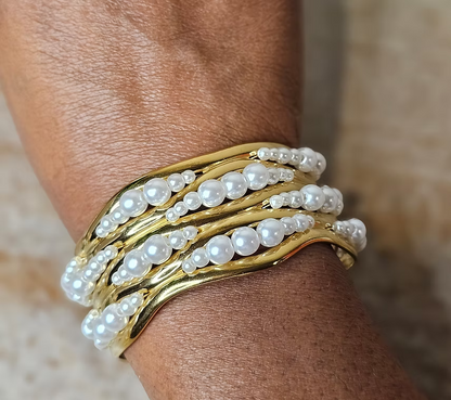18k Gold and pearl bracelet on a wrist with a neutral background