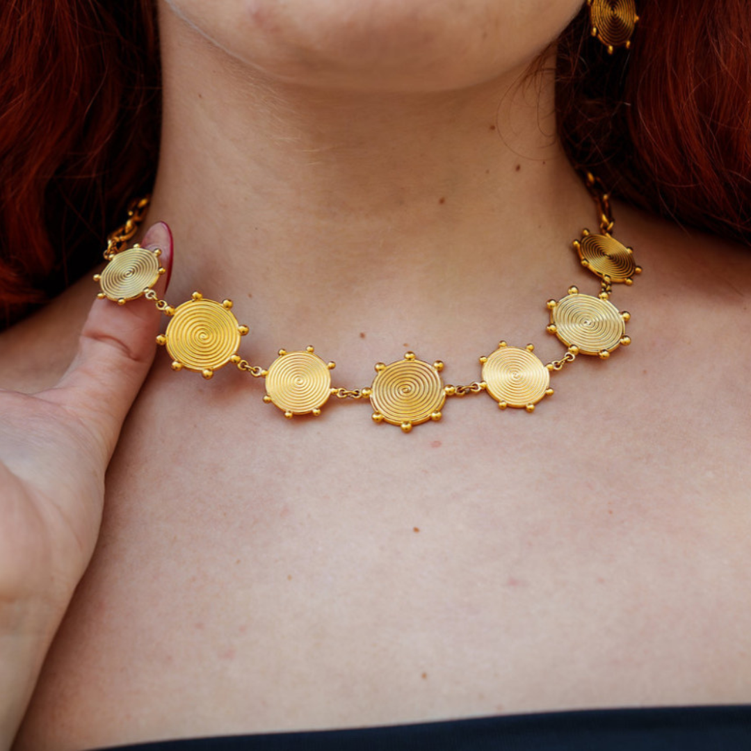 Gold necklace with circular designs worn by a person