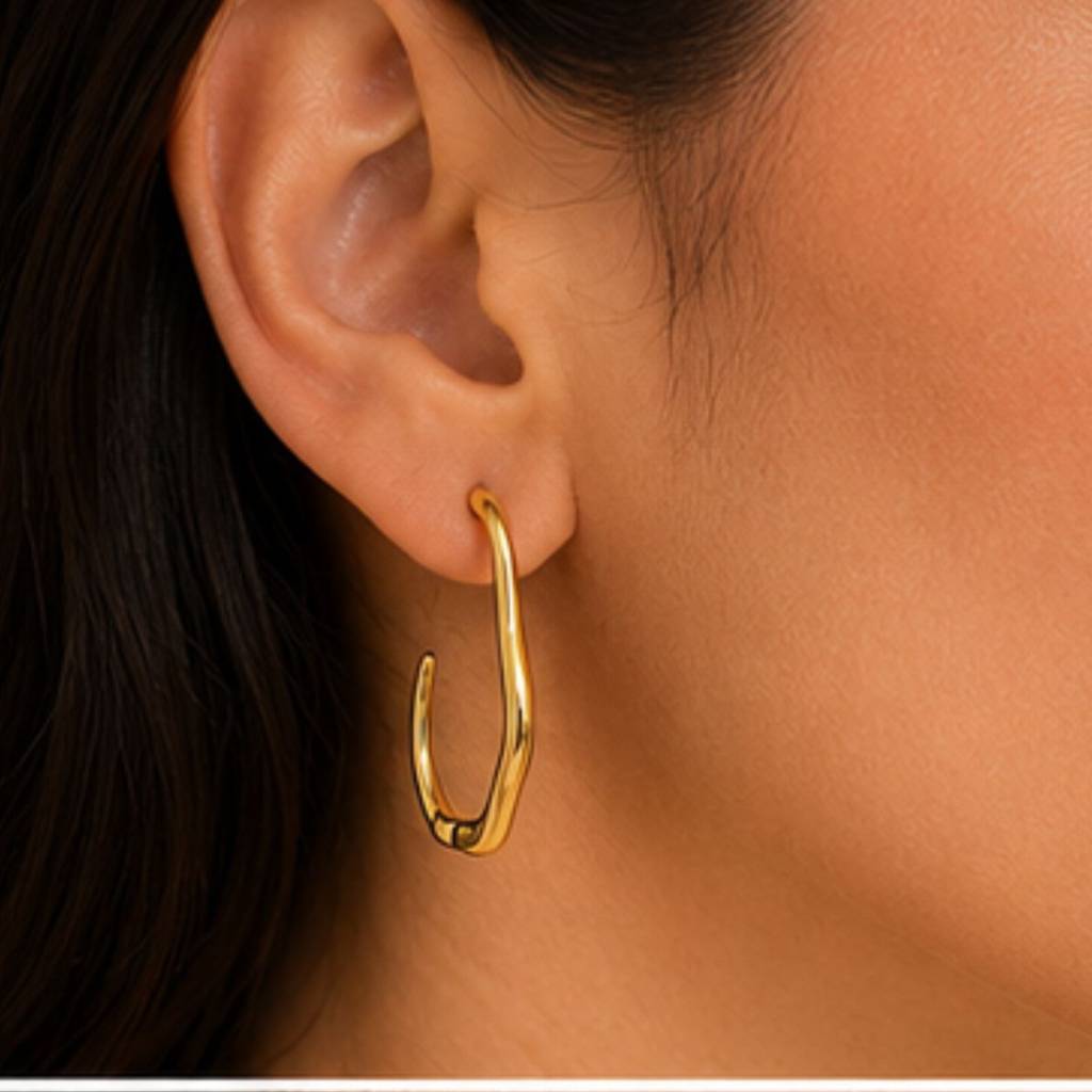 Gold hoop earring worn by a person with dark hair.