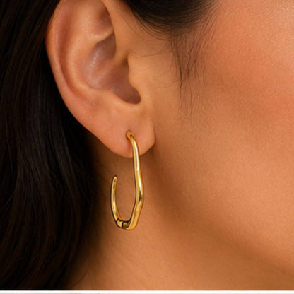 Gold hoop earring worn by a person with dark hair.