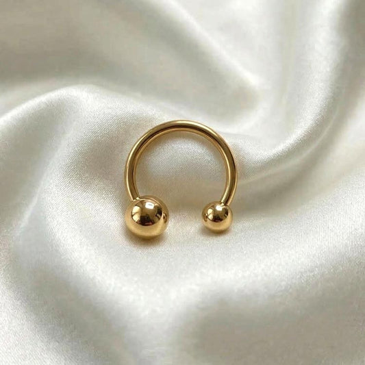 Gold hoop earring with two spherical ends on a white satin background
