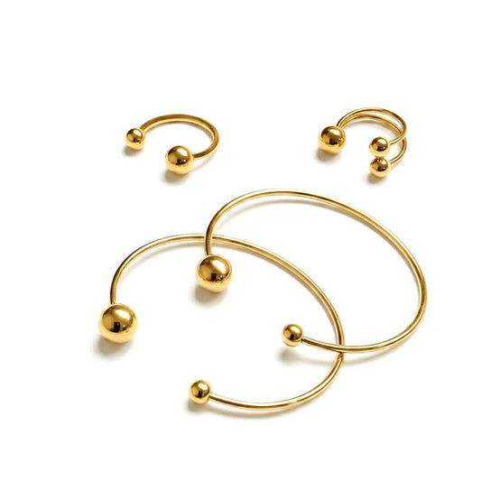 Set of gold hoop earrings with spherical accents on a white background