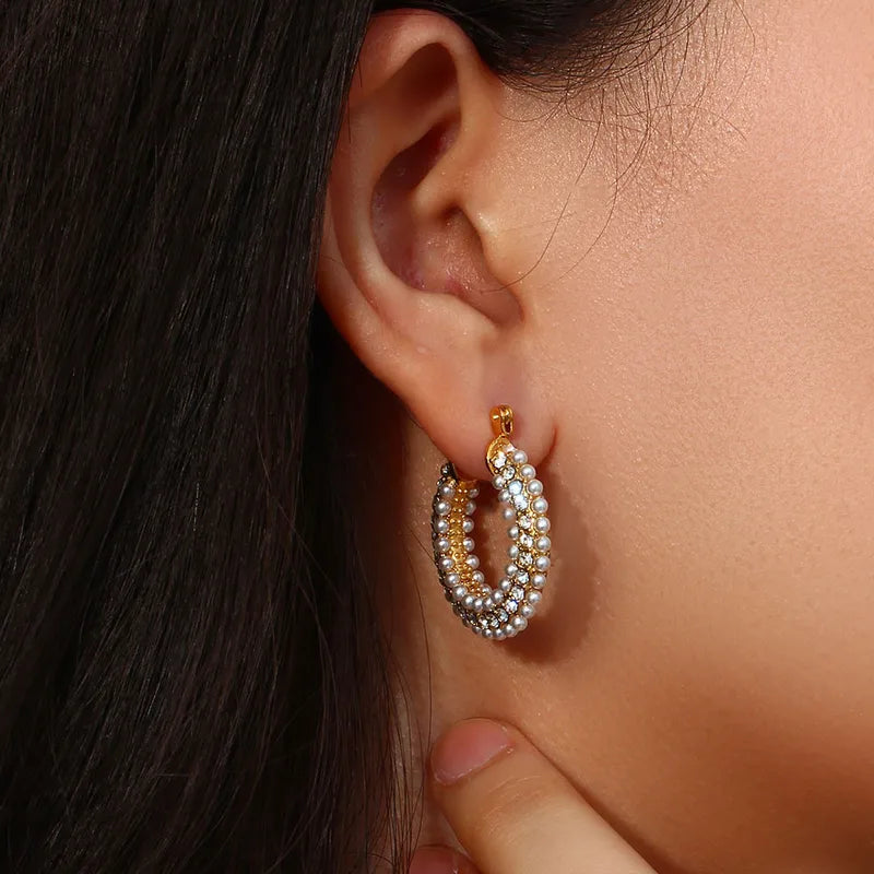 Close-up of an ear wearing a gold and pearl hoop earring.
