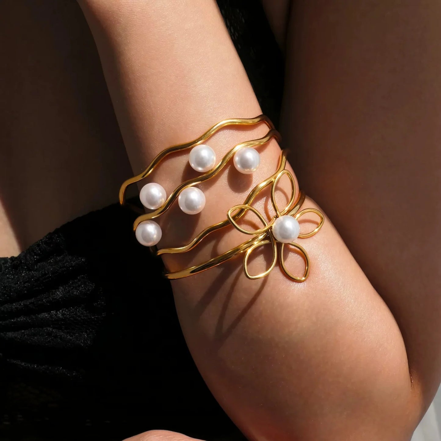 Gold bracelet with pearl beads on a person's wrist against a neutral background