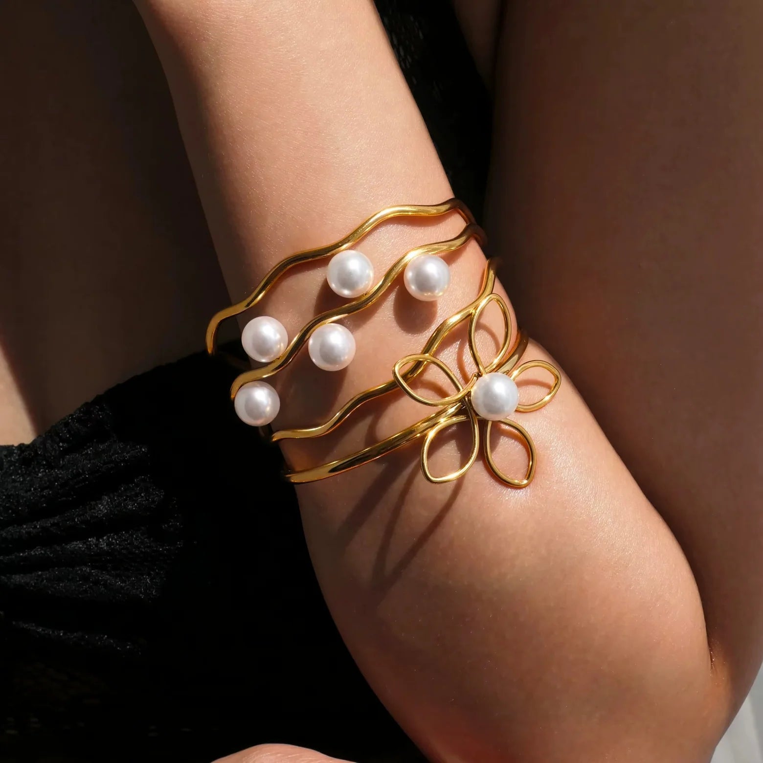 Gold bracelet with pearl beads on a person's wrist against a neutral background