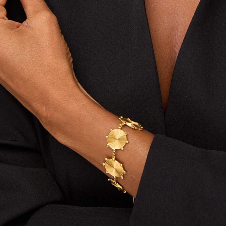 Gold bracelet on a person's wrist with a black outfit