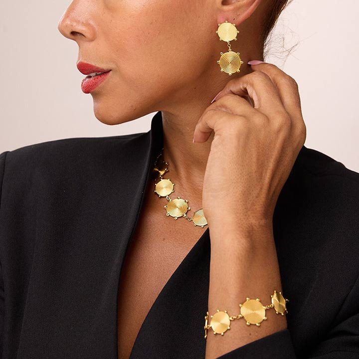 Woman wearing gold earrings, necklace and bracelet set