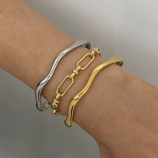 Two gold and silver bracelets on a wrist against a neutral background