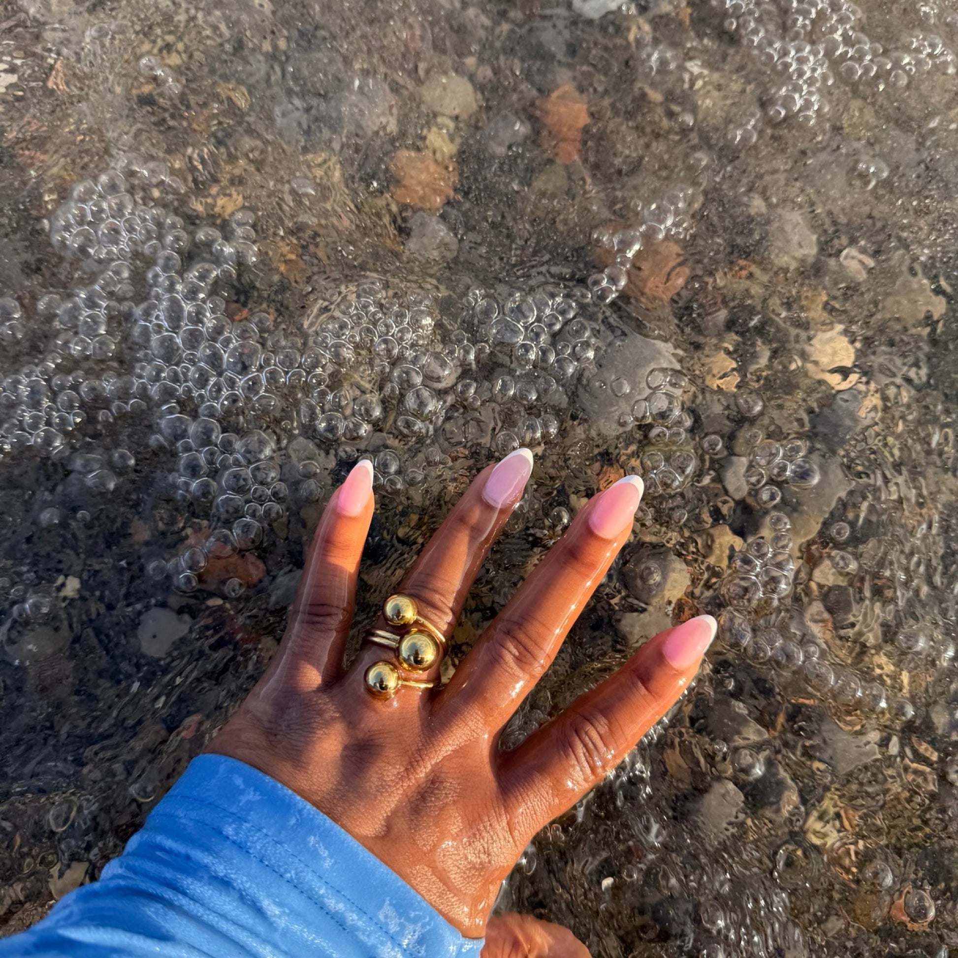 Hand with gold rings on a textured stone surface